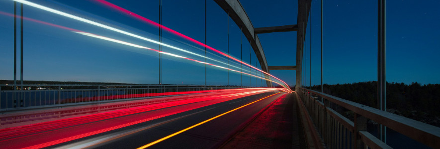 Eine moderne Brücke mit roten und weißen Lichtstreifen von fahrenden Autos, die durch eine Langzeitbelichtung eingefangen wurden.