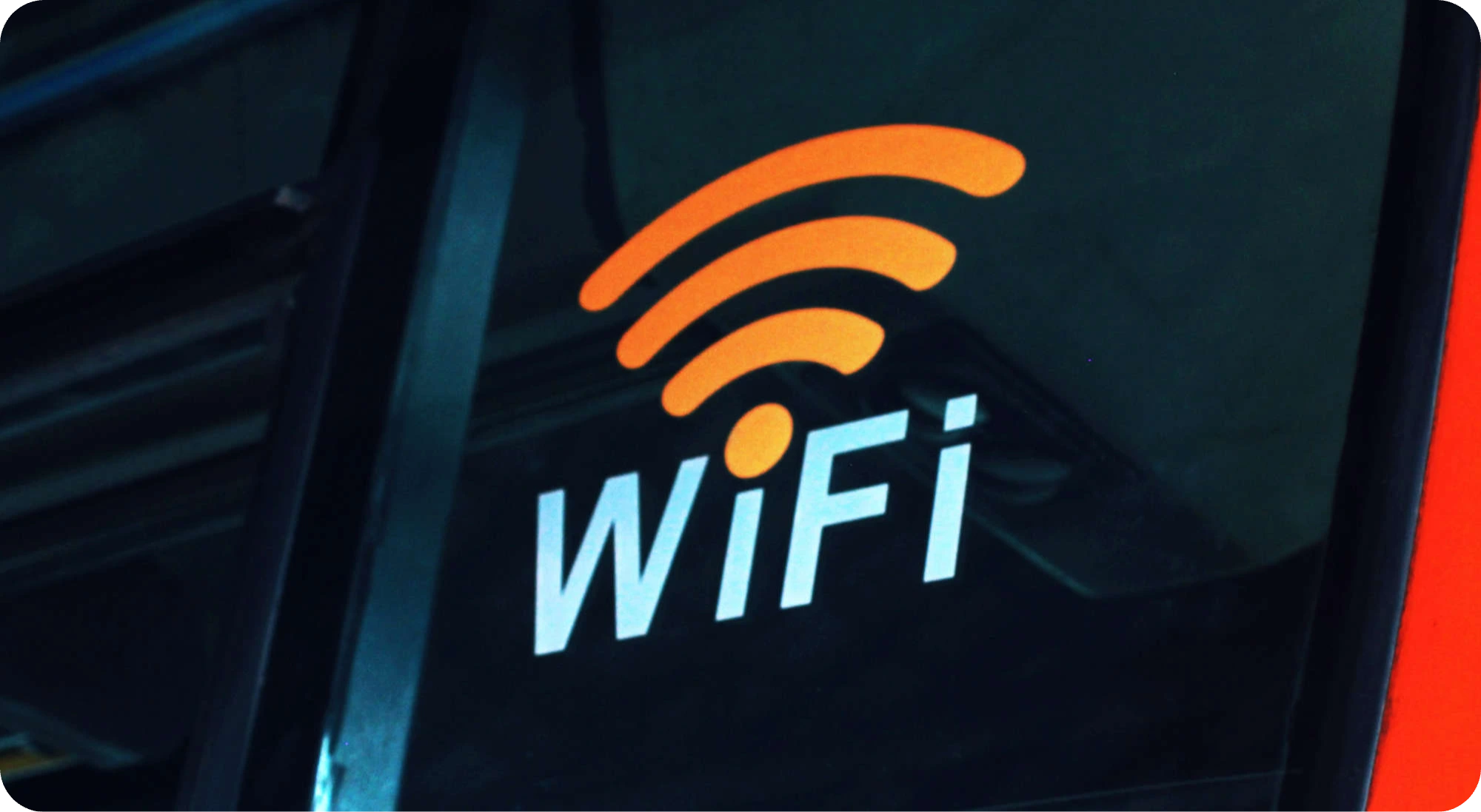 Nahaufnahme eines leuchtenden „WiFi“-Schriftzugs auf einer reflektierenden Glasfläche, das eine Verbindung zum drahtlosen Internet symbolisiert.