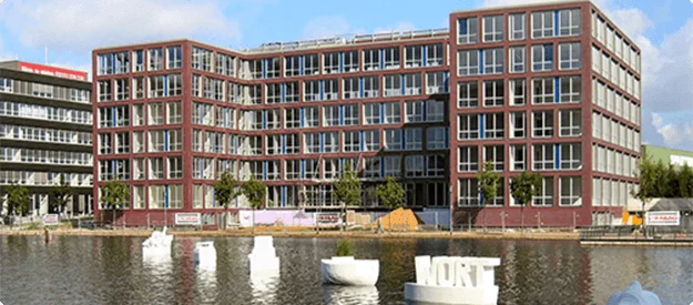 Ansicht des Duisburger Innenhafens mit modernen Bürogebäuden und Skulpturen im Wasser.